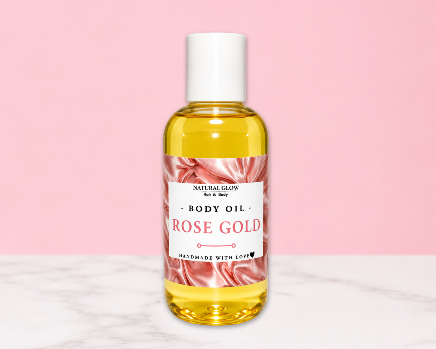 A bottle of Natural Glow Rose Gold Body Oil with a white cap, set against a solid pink background and a white marble surface.