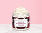 Natural Glow Black Raspberry Sugar whipped body butter in a jar with cream-colored butter swirl, pink background, and white marble surface