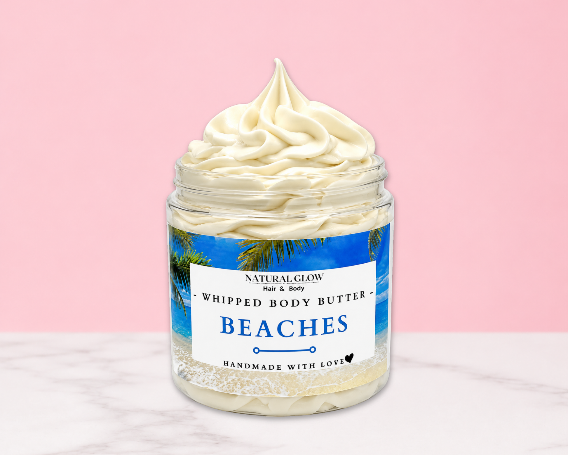 Natural Glow Beaches whipped body butter in a jar with cream-colored butter swirl, pink background, and white marble surface