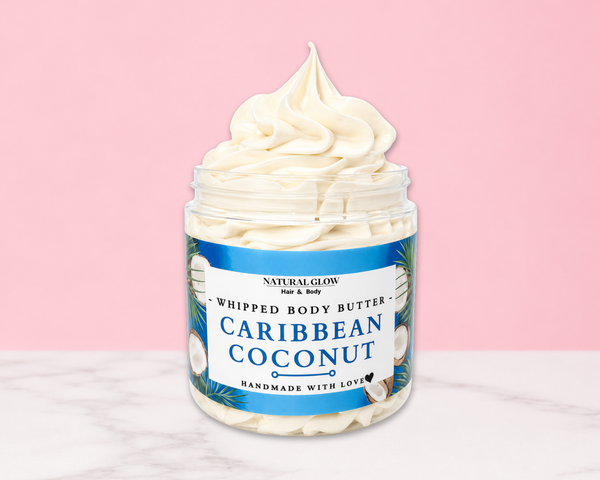 Natural Glow Caribbean Coconut whipped body butter in a jar with cream-colored butter swirl, pink background, and white marble surface