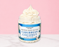 Natural Glow Caribbean Coconut whipped body butter in a jar with cream-colored butter swirl, pink background, and white marble surface