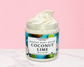 Natural Glow Coconut Lime whipped body butter in a jar with cream-colored butter swirl, pink background, and white marble surface