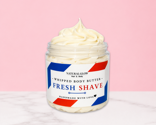 Natural Glow Fresh Shave men's whipped body butter in a jar with cream-colored butter swirl, pink background, and white marble surface