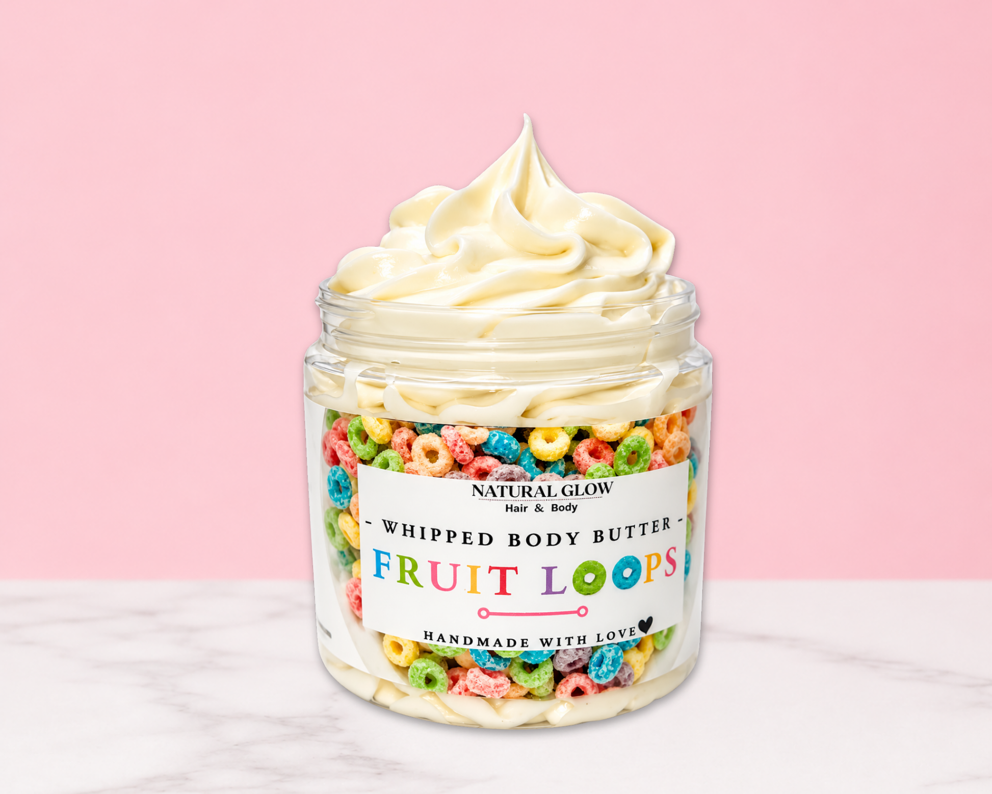 Natural Glow Fruit Loops whipped body butter in a jar with cream-colored butter swirl, pink background, and white marble surface