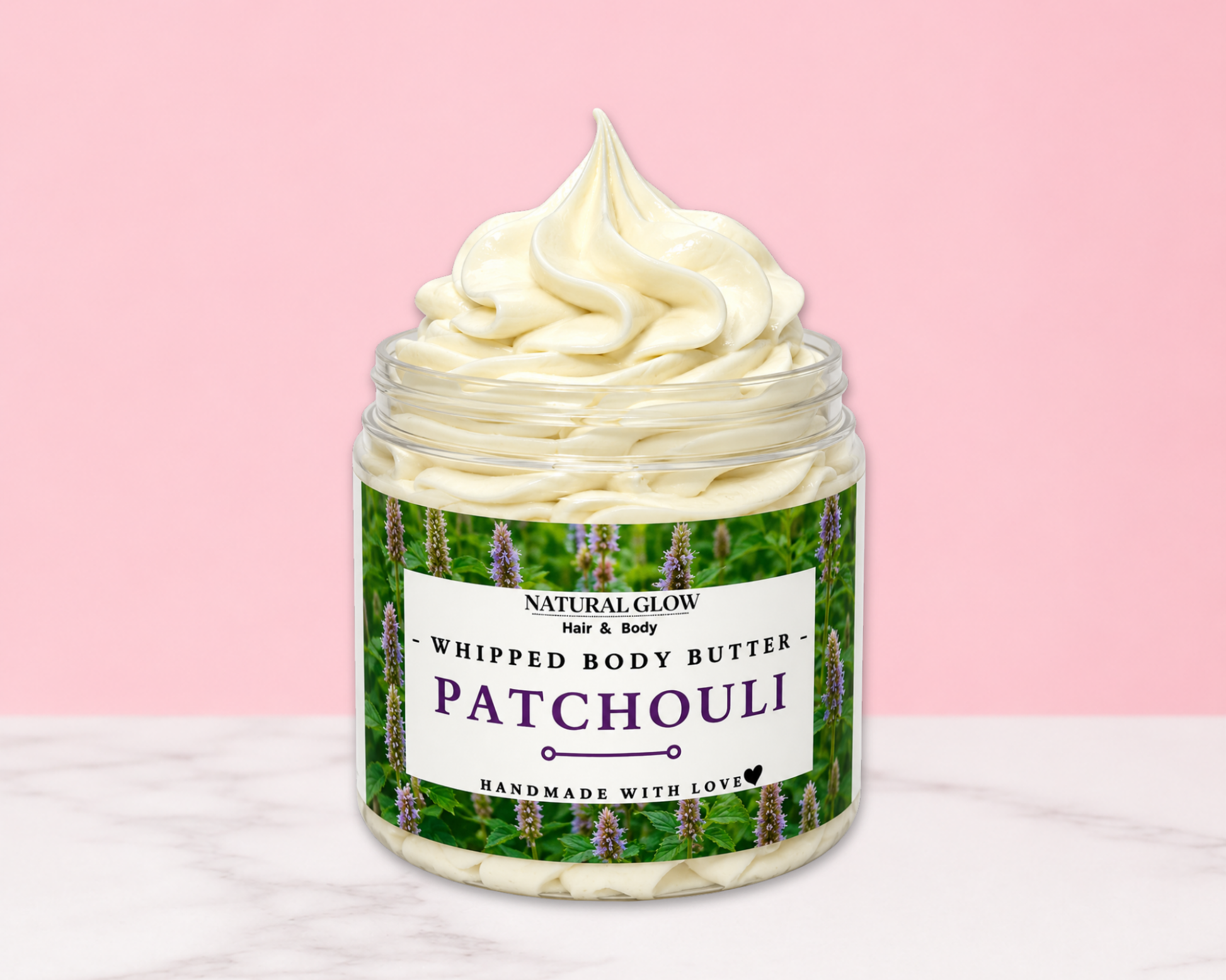 Natural Glow Patchouli whipped body butter in a jar with cream-colored butter swirl, pink background, and white marble surface