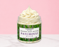 Natural Glow Patchouli whipped body butter in a jar with cream-colored butter swirl, pink background, and white marble surface
