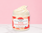 Natural Glow Pink Grapefruit whipped body butter in a jar with cream-colored butter swirl, pink background, and white marble surface