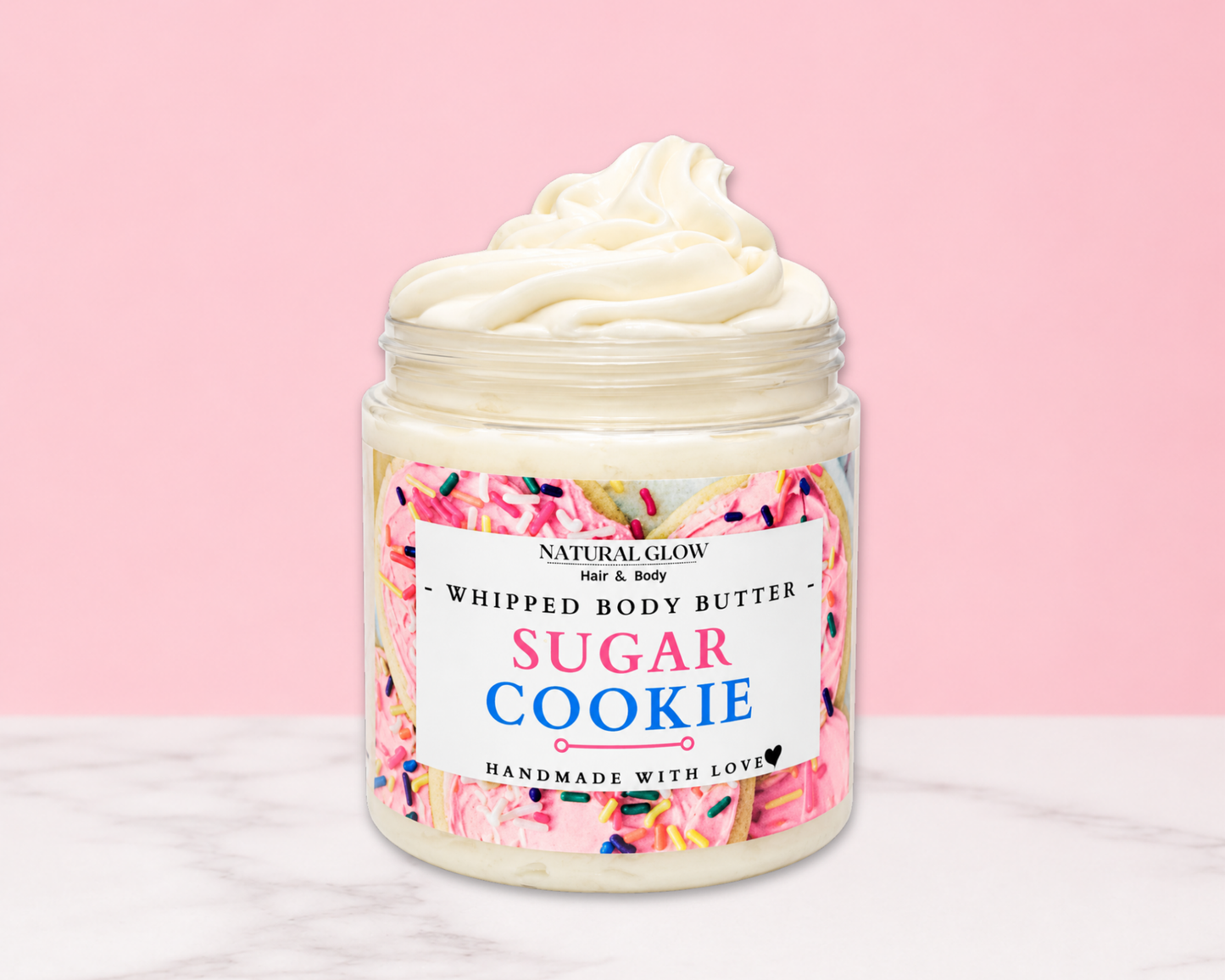 Natural Glow Sugar Cookie whipped body butter in a jar with cream-colored butter swirl, pink background, and white marble surface