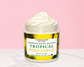 Natural Glow Tropical Pineapple whipped body butter in a jar with cream-colored butter swirl, pink background, and white marble surface