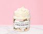 Natural Glow Unscented whipped body butter in a jar with cream-colored butter swirl, pink background, and white marble surface