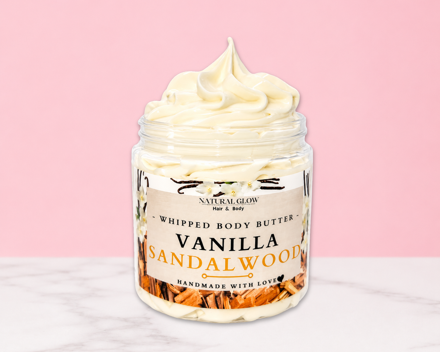 Natural Glow Vanilla Sandalwood whipped body butter in a jar with cream-colored butter swirl, pink background, and white marble surface