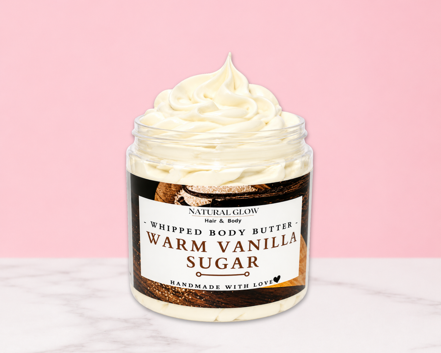 Natural Glow Warm Vanilla Sugar whipped body butter in a jar with cream-colored butter swirl, pink background, and white marble surface