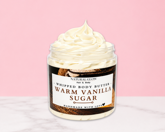 Natural Glow Warm Vanilla Sugar whipped body butter in a jar with cream-colored butter swirl, pink background, and white marble surface