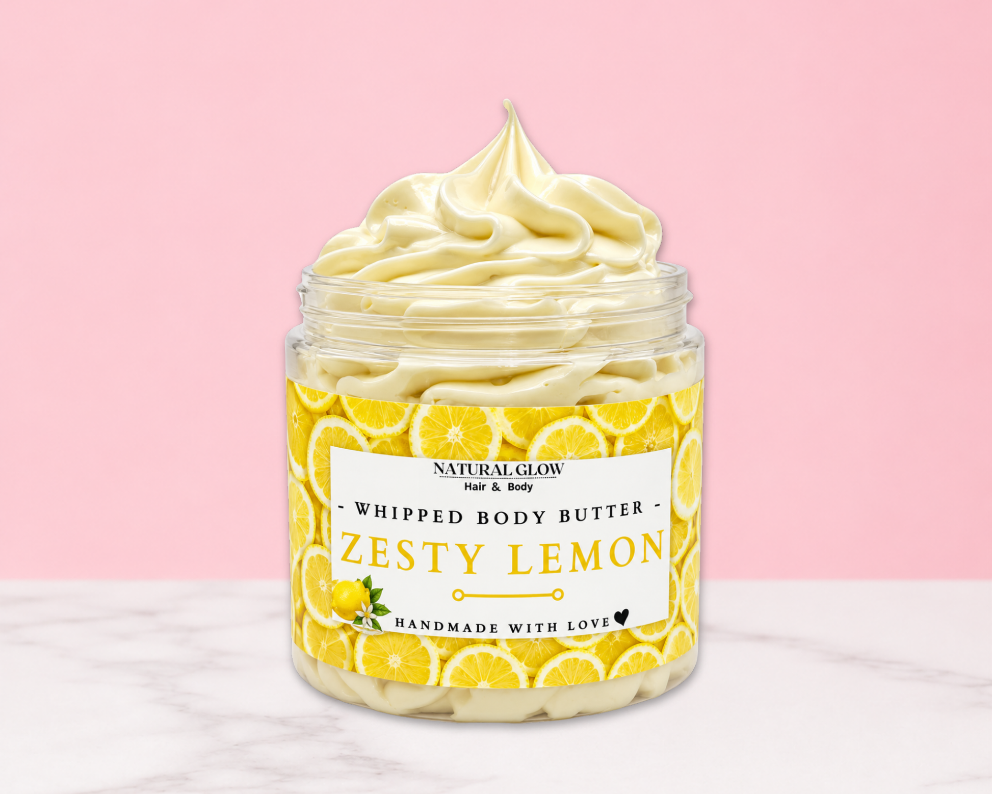 Natural Glow Zesty Lemon whipped body butter in a jar with cream-colored butter swirl, pink background, and white marble surface
