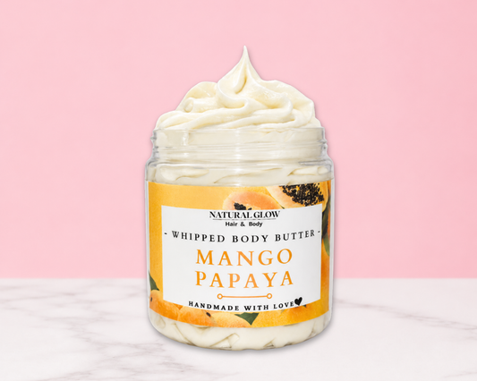 Natural Glow Mango Papaya whipped body butter in a jar with cream-colored butter swirl, pink background, and white marble surface