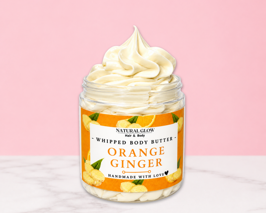 Natural Glow Orange Ginger whipped body butter in a jar with cream-colored butter swirl, pink background, and white marble surface