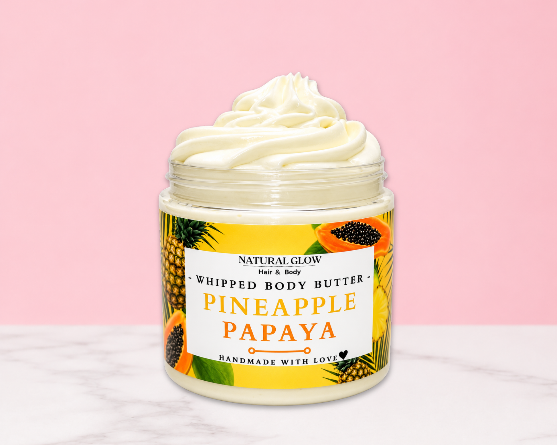 Natural Glow Pineapple Papaya whipped body butter in a jar with cream-colored butter swirl, pink background, and white marble surface